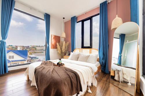 a bedroom with a large bed with blue curtains at Beyoung Hotel Dalat in Da Thanh