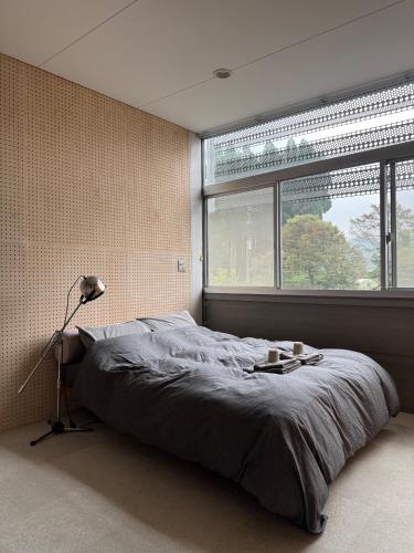 a bedroom with a bed with a lamp and a window at OGUNI S HOUSE 2F Designed by Toyo Ito in Oguni