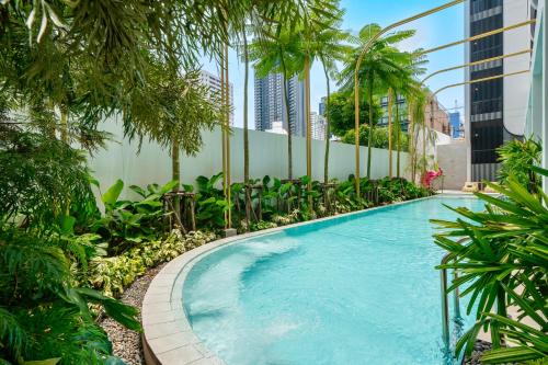 a swimming pool in a building with palm trees at Hotel Bangkokian in Bangkok