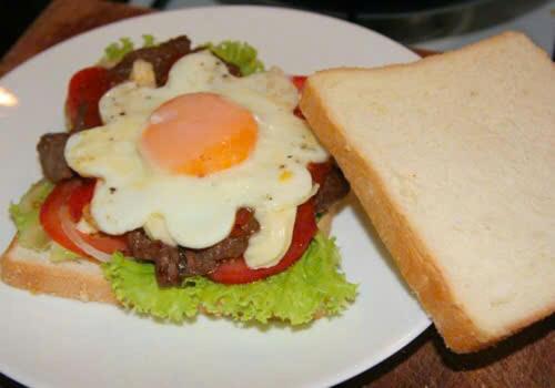 ein Sandwich mit einem Ei oben drauf auf einem weißen Teller in der Unterkunft Tamcoc Athletic Bungalow & Restaurant in Ninh Bình