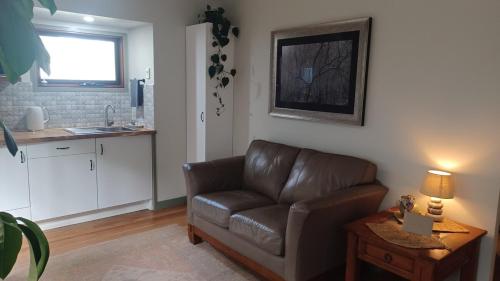 a living room with a leather couch and a table at Ferntree Hollow - private, peaceful, walk to town in Maleny