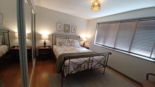 a bedroom with a bed with two lamps and a window at Ferntree Hollow - private, peaceful, walk to town in Maleny