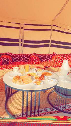 stół z talerzami z jedzeniem i kanapą w obiekcie Sand Oasis camp w mieście Al Ghabbī