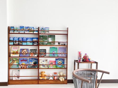 a book shelf filled with books next to a chair at Per La Villa Khao Lak in Khao Lak