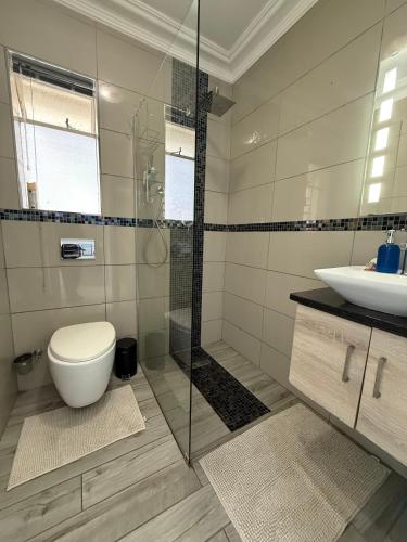 a bathroom with a shower and a toilet and a sink at The Ocean Nook - Modern Beach Condo in Gqeberha