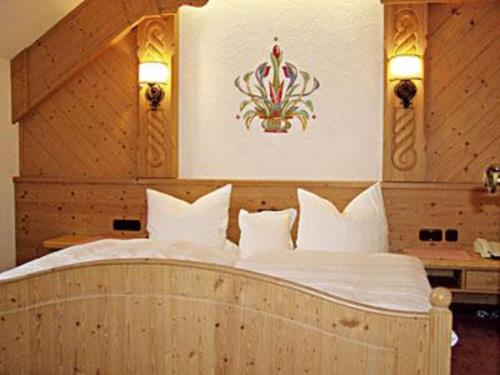 una camera da letto con letto in legno, lenzuola e cuscini bianchi di Gasthof Genosko a Spiegelau
