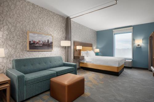 シンシナティにあるHome2 Suites By Hilton Cincinnati Eastgateのベッドとソファのあるホテルの部屋