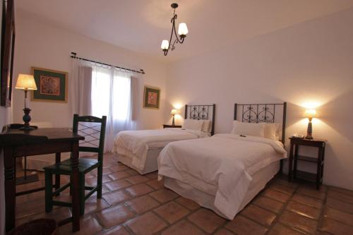 a bedroom with two beds and a table and a desk at La Merced Del Alto in Cachí