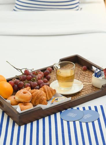 Soul Vacation Resort and Spa,Colva في كلفا: صينية من الخبز والعنب وكوب من الشاي