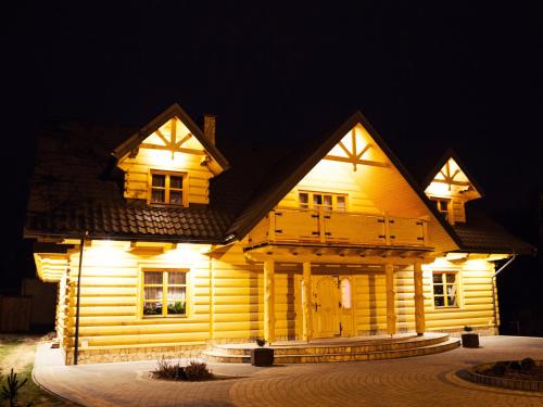 a large wooden house with lights on it at night at Agroturystyka Olszynka in Skopanie
