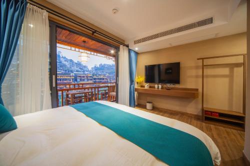 a bedroom with a large bed and a large window at Fenghuang Sulv Yunzhu River View Homestay in Fenghuang