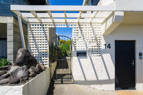 une passerelle menant à un bâtiment avec une porte noire dans l'établissement Waterfront On Woolcombe - 4BR holiday apartment, à New Plymouth