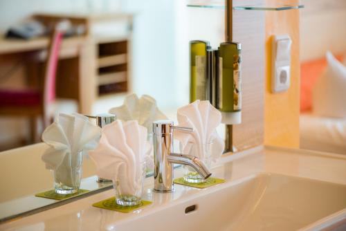 a bathroom sink with two glasses and a faucet at Hotel Walserberg in Warth am Arlberg