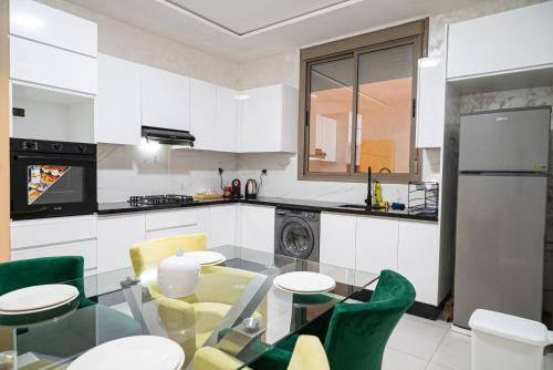 cocina con mesa de cristal y sillas verdes en URBAN WHITE Elya 1, en Beni Mellal