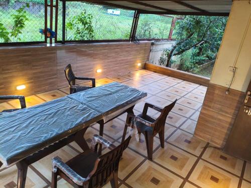 un patio con tavolo e sedie e una grande finestra di Bungalow a Lonavala