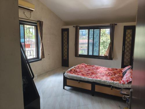 a bedroom with a bed in a room with two windows at Bungalow in Lonavala