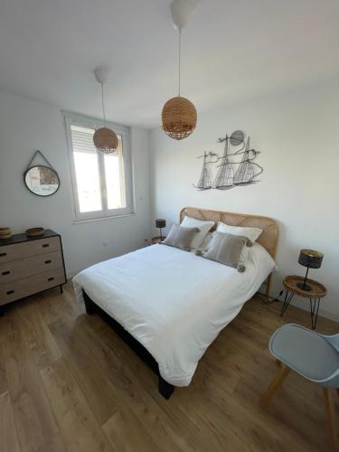 a bedroom with a white bed and a wooden floor at L'Escale Sètoise in Sète