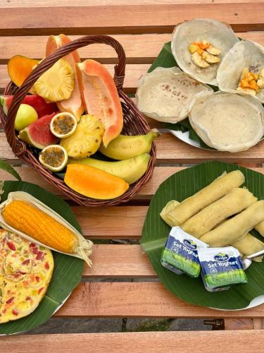 een houten tafel met borden met fruit en groenten bij The Palace Eco Cottage in Ella