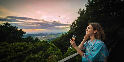 a woman holding a cell phone while standing on a ledge at Kaze no Tani no Iori in Gamagori