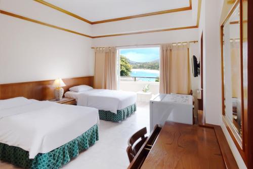 卡塔海滩Kata Sun Beach Hotel的有两张床和一扇大窗户的酒店房间