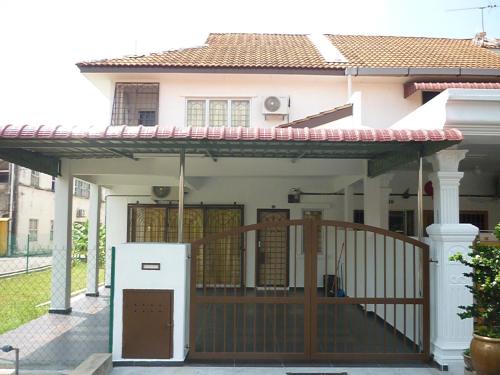 a house with a porch with a gate and a refrigerator at Super Cozy Homestay in Melaka