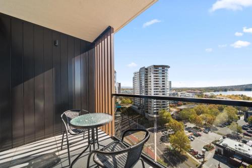 a balcony with a table and chairs and a view of a city at Sleek 2-Bed Apartment with Rooftop Garden Access in Belconnen