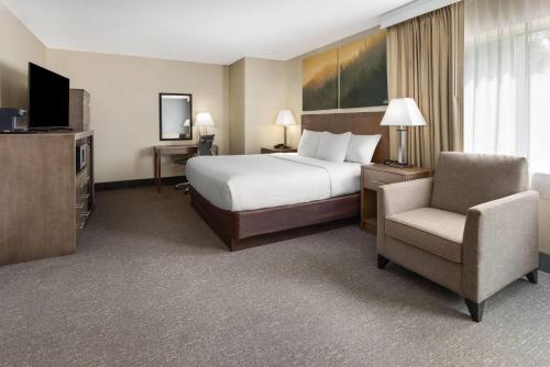 a hotel room with a bed and a chair at Days Inn by Wyndham Penn State in State College