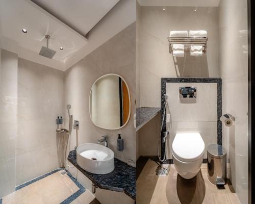 ein Badezimmer mit Toilette, Waschbecken und Spiegel in der Unterkunft Playotel Resort Indore in Indore