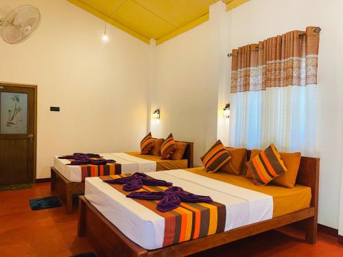 a hotel room with two beds and a couch at Liyara Lodge Sigiriya in Sigiriya