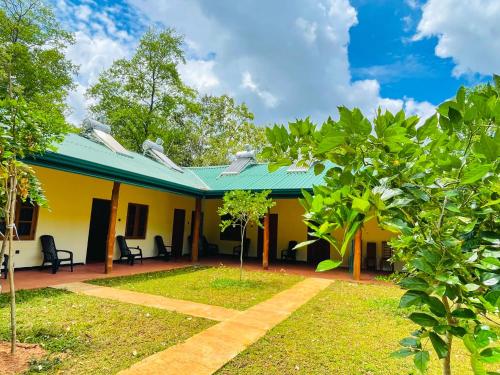 a yellow house with a green roof at Liyara Lodge Sigiriya in Sigiriya