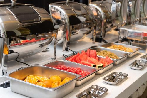 uma linha de buffet com várias bandejas de comida em REZEN LONGUU Hotel Guangzhou Baiyun International Airport em Huadu