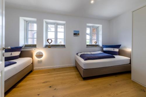 una camera da letto con due letti e due finestre di Haus Kniepsand, Wohnung Treibsand a Wittdün