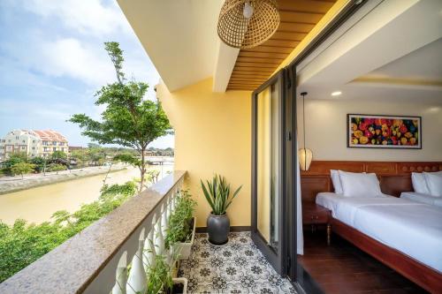 a balcony with a bed and a view of a river at Virgo Villa Quê Hội An in Hoi An