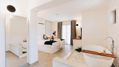 a woman sitting on a bed in a white room at BK Hotel in Fethiye