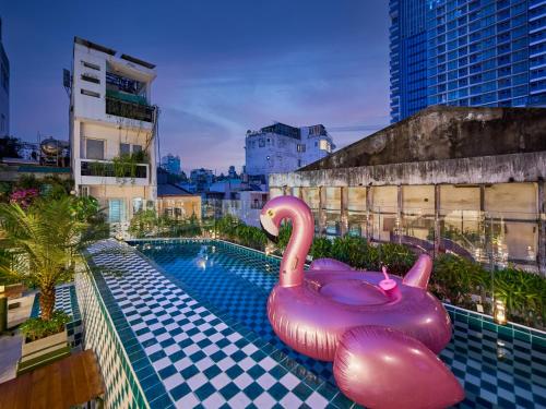 a swimming pool with a pink inflatable swan on a building at Cozy Room Featuring Local Rattan & Bamboo in Ho Chi Minh City
