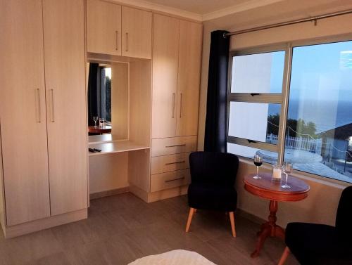 a kitchen with a table and a chair and a window at See n Bos in Gqeberha