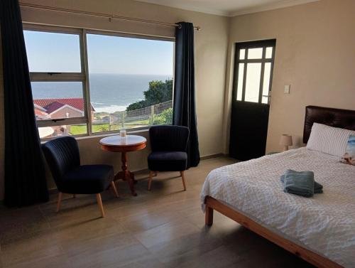 a bedroom with a bed and a view of the ocean at See n Bos in Gqeberha