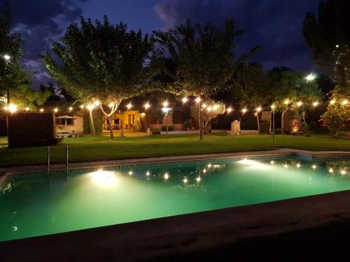 a swimming pool with lights in a yard at night at Complejo rural la Badia in Lucillos