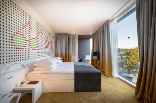 a hotel room with a bed and a large window at Maistra Select Family Hotel Amarin in Rovinj