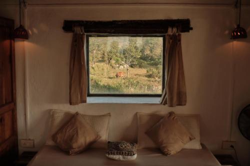 a window above a couch with a cow in a field at The Attic Library by AVVAs Stays in Bīr