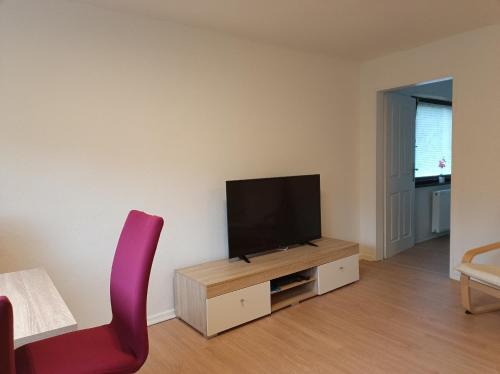 a living room with a tv and a red chair at Ferienwohnung Schack in Hoisdorf