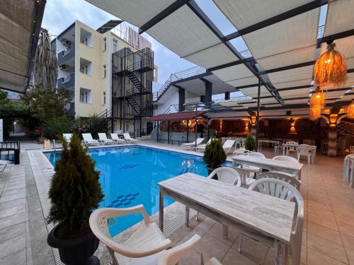 an outdoor patio with a table and chairs and a pool at BEGONYA HOTEL KEMER-All İnclisuve in Antalya