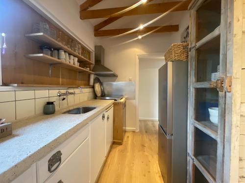 a kitchen with white cabinets and a wooden floor at Kust 1 in Egmond aan Zee