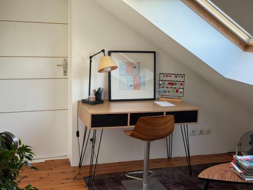 Un escritorio con una lámpara y una silla en una habitación. en Chambre hôtes nichée sous les toits, en Rennes