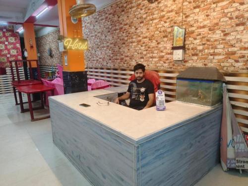 a man sitting at a counter in a restaurant at Meera Hotel And Lodging in Badarpur