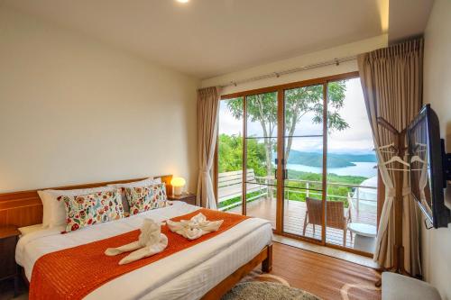 a bedroom with a bed and a large window at The Hilltop Erawan in Si Sawat