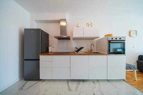a kitchen with white cabinets and a black refrigerator at Flex SelfCheckIns 191 - Zagreb - 2 Bedrooms - Parking - Loggia in Zagreb
