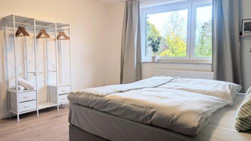 a white bedroom with a bed and a window at HYGGE HOMES - Apartment 'Stilla' in Celle
