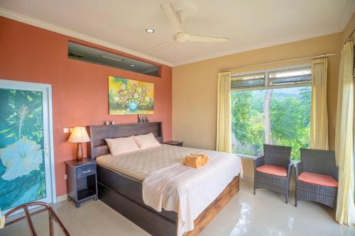 Un dormitorio con una cama y dos sillas y una ventana. en Maria Secret Villa, en Lovina