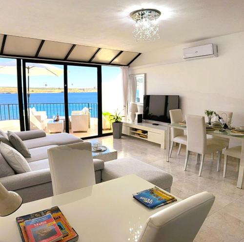 a living room with a couch and a table and a television at Seafront apartment 2 bedrooms Terrace & Panoramic ocean views in Is-Sellum